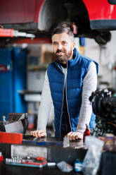 Porträt eines männlichen Mechanikers in einer Autowerkstatt. - HPIF27319