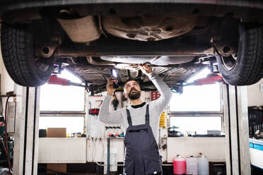 Älterer Mann, der ein Auto in einer Garage repariert. - HPIF27321