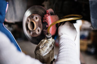 Ein nicht erkennbarer männlicher Mechaniker repariert ein Auto in einer Werkstatt. - HPIF27331