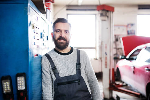 Porträt eines Mannes, der als Mechaniker in einer Garage steht. - HPIF27338