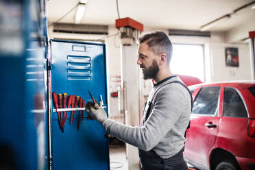 Porträt eines Mannes, der als Mechaniker in einer Garage steht. - HPIF27340