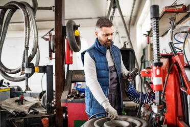 Älterer Mann, der ein Auto in einer Garage repariert. - HPIF27341