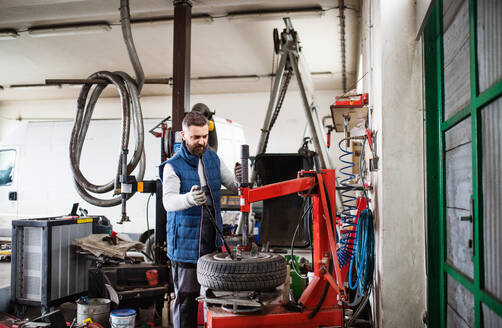 Älterer Mann, der ein Auto in einer Garage repariert. - HPIF27342