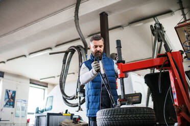 Älterer Mann, der ein Auto in einer Garage repariert. - HPIF27343