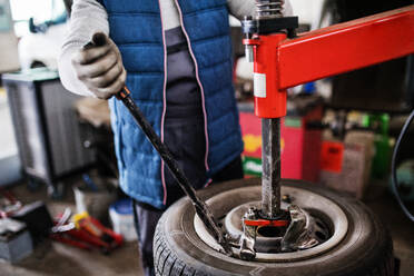 Unrcognizable man mechanic repairing a car in a garage. - HPIF27345