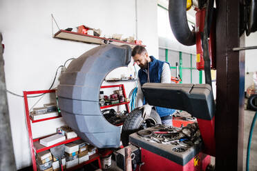 Älterer Mann, der ein Auto in einer Garage repariert. - HPIF27346