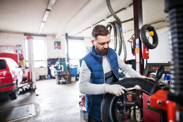 Älterer Mann, der ein Auto in einer Garage repariert. - HPIF27348