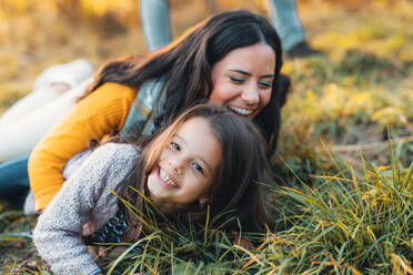 A portrait of young mother with a small daughter lying on a ground in autumn nature. - HPIF27402