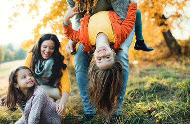 Ein Porträt einer glücklichen jungen Familie mit zwei kleinen Kindern in der herbstlichen Natur, die Spaß haben. - HPIF27403