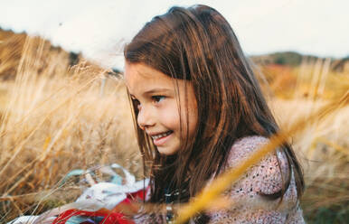 A happy small girl playing with a rainbow hand kite in autumn nature. - HPIF27406