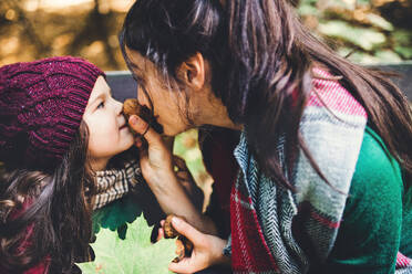 Eine junge Mutter mit einem Kleinkind Tochter haben Spaß mit Nüssen im Wald im Herbst Natur. - HPIF27418