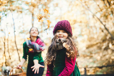 Ein Porträt von Kleinkind Mädchen mit unerkennbaren Mutter im Wald im Herbst Natur, Spaß haben. - HPIF27430