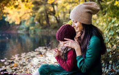 Eine Seitenansicht der jungen Mutter mit einem Kleinkind Tochter sitzen im Wald im Herbst Natur. - HPIF27451