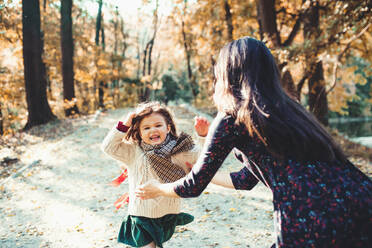 A portrait of young mother with a toddler daughter running in forest in autumn nature. - HPIF27460