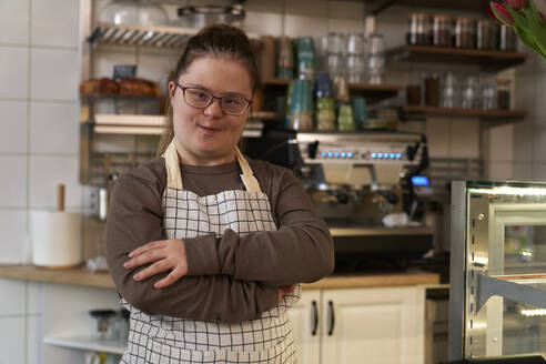 Lächelnder Café-Besitzer mit Down-Syndrom steht im Café - ABIF02009