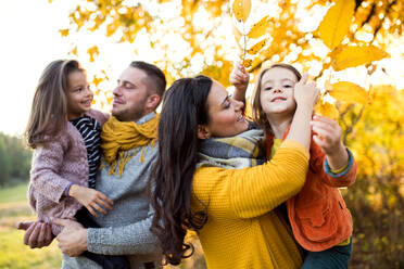 Ein Porträt einer glücklichen jungen Familie mit zwei kleinen Kindern in herbstlicher Natur. - HPIF27487