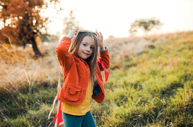 Ein glückliches kleines Mädchen, das mit einem Regenbogen-Handdrachen in der herbstlichen Natur bei Sonnenuntergang spielt. Copy Space. - HPIF27496