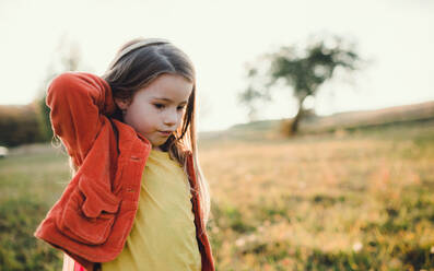 Ein kleines Mädchen, das bei Sonnenuntergang in der herbstlichen Natur spazieren geht und spielt. Copy space. - HPIF27498