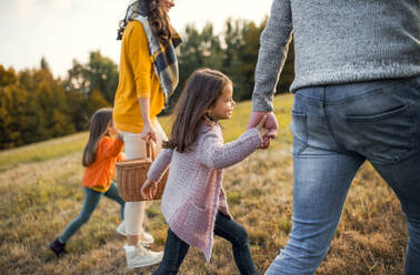 Eine Mittelansicht einer glücklichen jungen Familie mit zwei kleinen Kindern, die in der herbstlichen Natur spazieren gehen. - HPIF27510