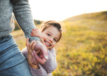 Ein glückliches kleines Mädchen mit unerkennbarem Vater in herbstlicher Natur, das Spaß hat. - HPIF27543
