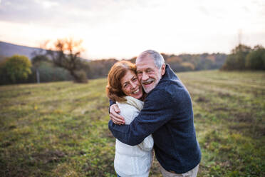 Senior couple in love on a walk in an autumn nature. Senior man and a woman hugging at sunset. Copy space. - HPIF27597