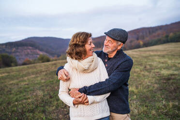 Senior couple in love on a walk in an autumn nature. Senior man and a woman hugging, looking at each other. Copy space. - HPIF27602
