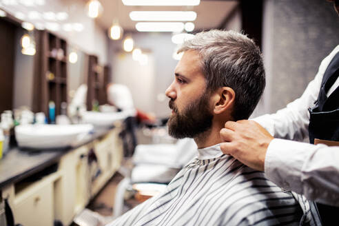 Gutaussehender Hipster-Mann, der einen Friseur und einen Haarstylisten im Friseursalon besucht. - HPIF27653