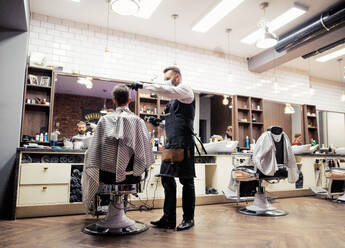 Handsome hipster man client visiting haidresser and hairstylist in barber shop. - HPIF27655