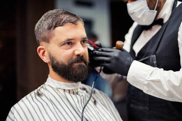 Gutaussehender Hipster-Mann, der einen Friseur und einen Haarstylisten im Friseursalon besucht. - HPIF27656