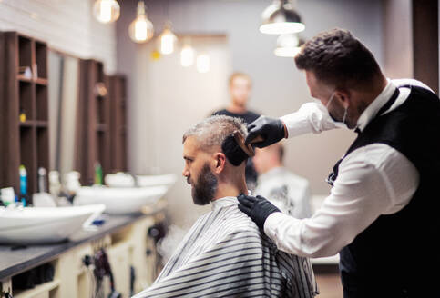 Gutaussehender Hipster-Mann, der einen Friseur und einen Haarstylisten im Friseursalon besucht. - HPIF27662