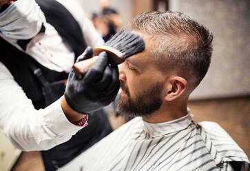 Gutaussehender Hipster-Mann, der einen Friseur und einen Haarstylisten im Friseursalon besucht. - HPIF27668