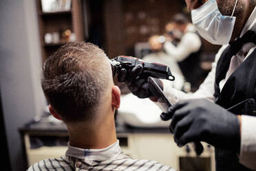 Rückansicht eines gut aussehenden Hipster-Mannes, der einen Friseur und einen Haarstylisten im Friseursalon besucht. - HPIF27669