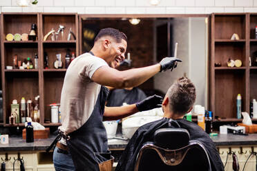 Rückansicht eines männlichen Kunden, der einen Friseur und einen Haarstylisten in einem Friseursalon besucht. - HPIF27675