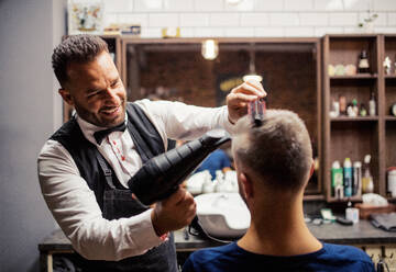 Gutaussehender Hipster-Mann, der einen Friseur und einen Haarstylisten im Friseursalon besucht. - HPIF27682