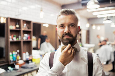 Ein Porträt eines gutaussehenden Hipster-Mannes, der in einem Friseursalon steht, Kopierraum. - HPIF27697