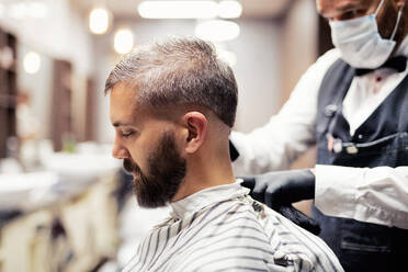 Gutaussehender Hipster-Mann, der einen Friseur und einen Haarstylisten im Friseursalon besucht. - HPIF27704