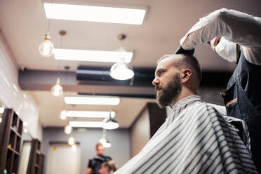 Gutaussehender Hipster-Mann, der einen Friseur und einen Haarstylisten im Friseursalon besucht. - HPIF27714