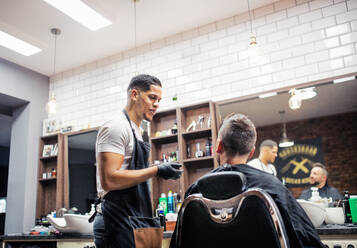Ein reifer Mann im Gespräch mit einem Friseur und einer Friseurin in einem Friseursalon. - HPIF27717