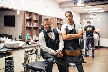 Zwei männliche Friseure und Hairstylisten sitzen in einem Friseursalon und posieren für ein Foto. - HPIF27732