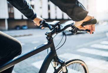 Nahaufnahme eines Geschäftsmannes mit Elektrofahrrad auf dem Weg zur Arbeit in der Stadt. - HPIF27753