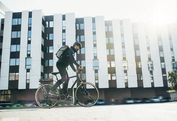 Männlicher Hipster-Kurier mit Fahrrad auf einer Straße in der Stadt, der Pakete ausliefert, Kopierraum. - HPIF27754