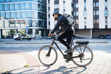 Männlicher Hipster-Kurier mit Fahrrad auf einer Straße in der Stadt, der Pakete ausliefert, Kopierraum. - HPIF27756