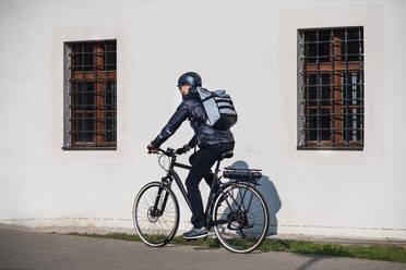 Eine Rückansicht eines Kuriers mit Fahrrad in der Stadt, der Pakete ausliefert. - HPIF27764