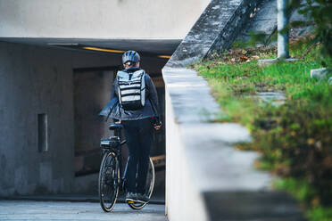 Rückansicht eines männlichen Fahrradkuriers, der in der Stadt Pakete ausliefert, Kopierraum. - HPIF27765