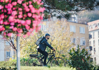 Seitenansicht eines Hipster-Geschäftsmannes mit Fahrrad auf dem Weg zur Arbeit in der Stadt. - HPIF27768