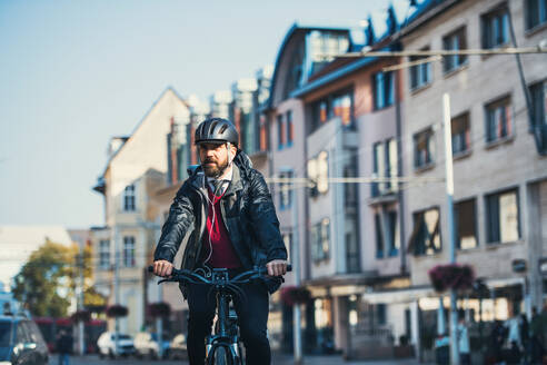 Hipster Geschäftsmann mit Elektrofahrrad auf dem Heimweg von der Arbeit in der Stadt. - HPIF27775