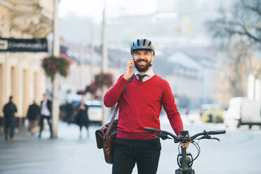 Hipster Geschäftsmann Pendler mit Fahrrad auf dem Weg zur Arbeit in der Stadt, stehend und mit Smartphone. - HPIF27778