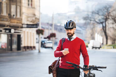 Hipster Geschäftsmann Pendler mit Fahrrad auf dem Weg zur Arbeit in der Stadt, stehend und mit Smartphone. - HPIF27780