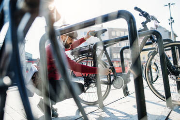 A hipster businessman commuter parking electric bicycle in city when going to work. - HPIF27785