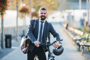 Ein Geschäftsmann mit Fahrrad auf dem Heimweg von der Arbeit in der Stadt. - HPIF27812